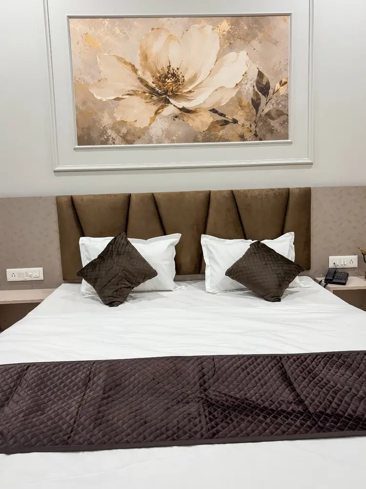 Queen bed with brown headboard and floral artwork