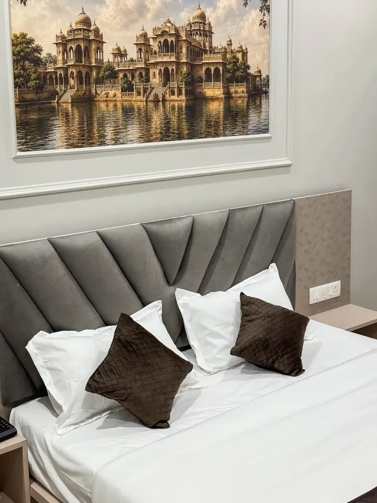 Queen bed with grey channel headboard below a lake palace painting