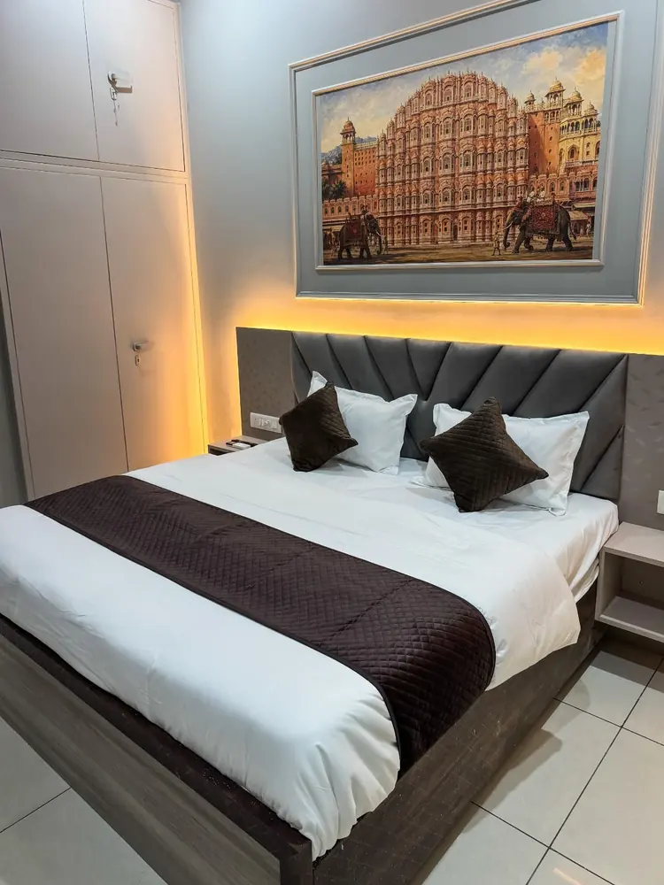 Queen bed under a Hawa Mahal painting with warm backlight